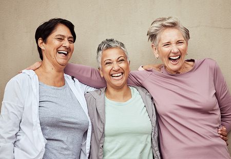Drei Damen mittleren Alters lachen gemeinsam